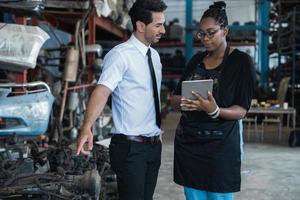 African woman working and check on tablet and talk with boss or customer in old part of car factory photo