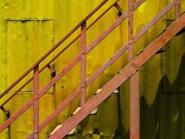 Close-up of rusty staircase aganst yellow steel cabin photo