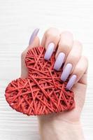 manos de niña con delicada manicura morada y corazón decorado foto