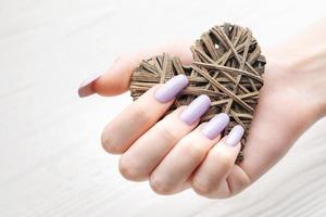 manos de niña con delicada manicura morada y corazón decorado foto