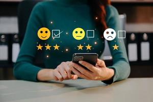 Customer service evaluation concept. Businesswoman pressing face smile emoticon show on virtual screen at tablet and smartphone in office photo