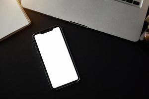 Top view workspace with blank screen smartphone. laptop on table photo