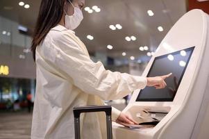 A traveller woman is wearing protective mask in International airport, travel under Covid-19 pandemic, safety travels, social distancing protocol, New normal travel concept photo