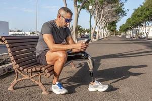 Male runner with disability using smartphone on street photo