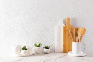 artículos ecológicos de vajilla moderna sobre una encimera de mármol blanco con plantas verdes en mini colinas. espacio para texto. estilo minimalista. foto