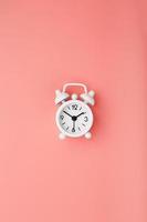 White retro alarm clock on pink background. Concept of time with free space for text.