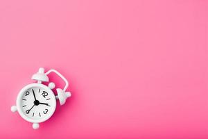 White retro alarm clock on pink background. Concept of time with free space for text. photo