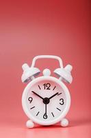 White retro alarm clock on pink background. Concept of time with free space for text. photo