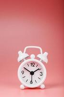 White retro alarm clock on pink background. Concept of time with free space for text. photo