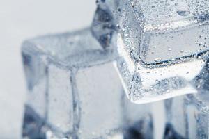 cubo de hielo con gotas de agua de cerca - en macro sobre un fondo blanco. hielo refrescante. aislar