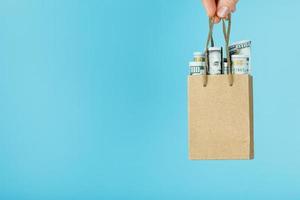 A small aid Bag made of paper in an outstretched hand with US dollars on a blue background. Packaging template layout with space for copying, advertising. photo