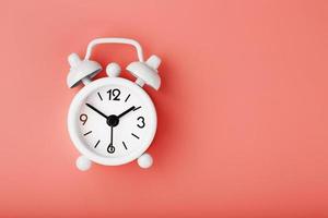 White retro alarm clock on pink background. Concept of time with free space for text. photo