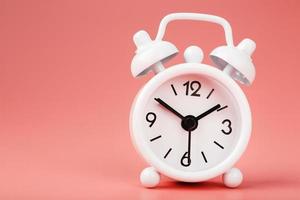 White retro alarm clock on pink background. Concept of time with free space for text. photo