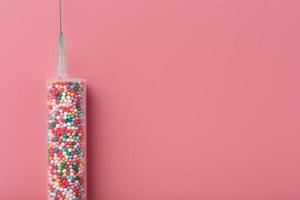 jeringa con globos de colores sobre un fondo rosa con espacio libre. foto