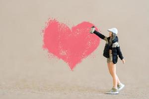 artista sosteniendo dispensador y rociando con formas de corazón rojo, concepto de día de san valentín foto