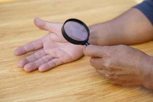 Closeup hand holds magnifying glass to inspect palm lines. Concept, palmistry, astrology. Foretelling, mystery, magic, fortune, fate. Prediction for future life , events.  Palmist predicting. photo