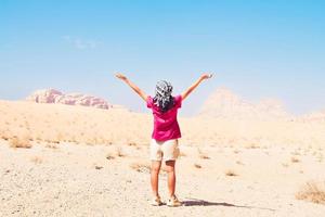Happy joyful woman tourist stand with hands up on wadi rum desert on hike on holiday vacation in Wadi rum. Popular Wadi Rum desert in Jordan photo