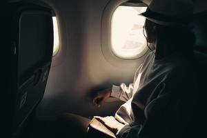 Young traveller woman sitting inside plane on flight watch to sky and plane wing from window photo
