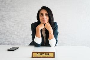 joven directora de mujer de negocios morena caucásica en el cargo. mujer de negocios aburrida pasando tiempo en la oficina. trabajador corporativo perezoso postergando el trabajo foto