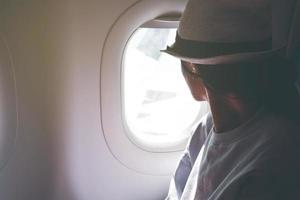 Woman looks out the window of an flying airplane wings view. Young passengers are traveling by plane, watching the sky from above photo