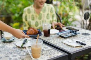 camarera sirviendo croissants en la cafetería al aire libre. foto