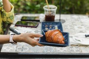 mano de mujer sosteniendo croissants en la mesa en el café al aire libre. foto