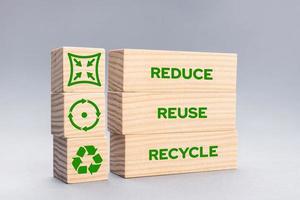 Reduce Reuse Recycle Icons and words on wooden blocks on gray background photo