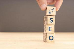 SEO or search engine optimization concept. Hand holding a wooden block with rocket icon and SEO word. Copy space photo