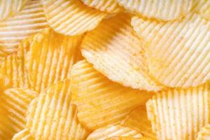 Yellow crispy ridged potato chips close up. Food background photo