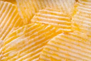 Yellow crispy ridged potato chips close up. Food background photo