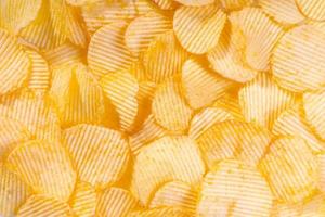 Yellow crispy ridged potato chips close up. Food background photo