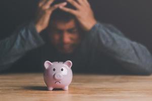 piggy bank and man with uneasiness,unsolvable financial problem concept,unemployment, poverty, unpaid debts,business loss, bankruptcy and crisis,Anxious about future financial crises photo