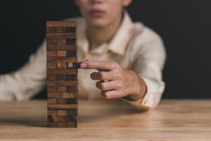 Businessman pulling a jenga wooden box,financial risk management and strategic planning,through data analysis for continuous improvement,Visionary Decisions for Leadership Success photo
