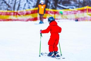 Little girl skiing downhill in winter equipment photo