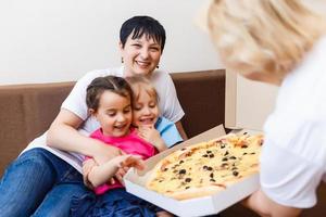 Portrait of happy family eating pizza while sitting on sofa at home photo