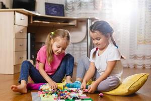 Two cute little children are playing with blocks happy girls at home funny lovely sisters photo