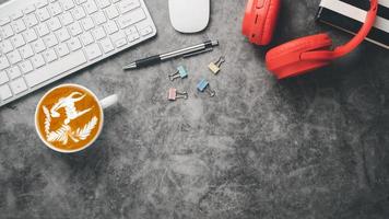 lugar de trabajo de oficina con computadora de teclado, mouse, computadora portátil, auriculares, bolígrafo y taza de café, vista superior plana con espacio de copia. foto