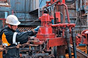 Astana, Kazakhstan, June 24, 2021- A working oil driller is engaged in spinning pump pressuring pipes on the well. photo