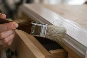 Woman painting a wooden bedside table with a brush photo