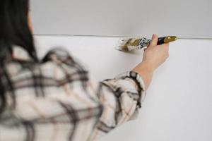 mujer pintando una pared con pintura blanca foto