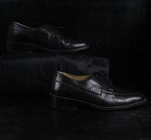 Pair of black male classic shoes on black background. Dusty shoes photo