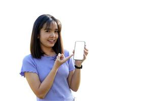 Smiling Asian woman playing and update new applications. Her hand pointed at the phone with blank screen workspace area chatting on white background. Soft and selective focus. photo