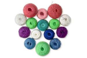 Multi-colored wool balls, yarn in shape of heart on isolated background. Concept of knitting, sewing, needlework, hobby, Valentine day photo