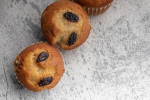 Banana cupcakes sprinkled with raisins. Copy space on gray background. photo