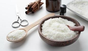 ingredients for candle making , soy wax flakes, candles, cinnamon wicks and wooden spoons on light marble background photo