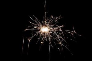 Burning sparkler isolated on black background. Fireworks theme. Light effect and texture. photo