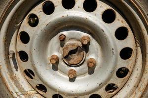 old rusty wheel in the sunlight. wheel rim, bolts and capped schrader valve. Close-up photo