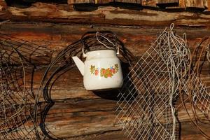 white teapot is hanging on the wooden wall. Log wall of the house. photo