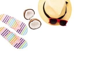 accesorios de verano. zapatos, sombrero, coco, gafas de sol. fondo de verano aislado en blanco. vista superior de chanclas. pantuflas a rayas foto