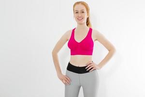 Young red haired girl in sport wear clothes isolated on white background. Slim body figure and healthy lifestyle. Fitness and sports concept. Banner photo